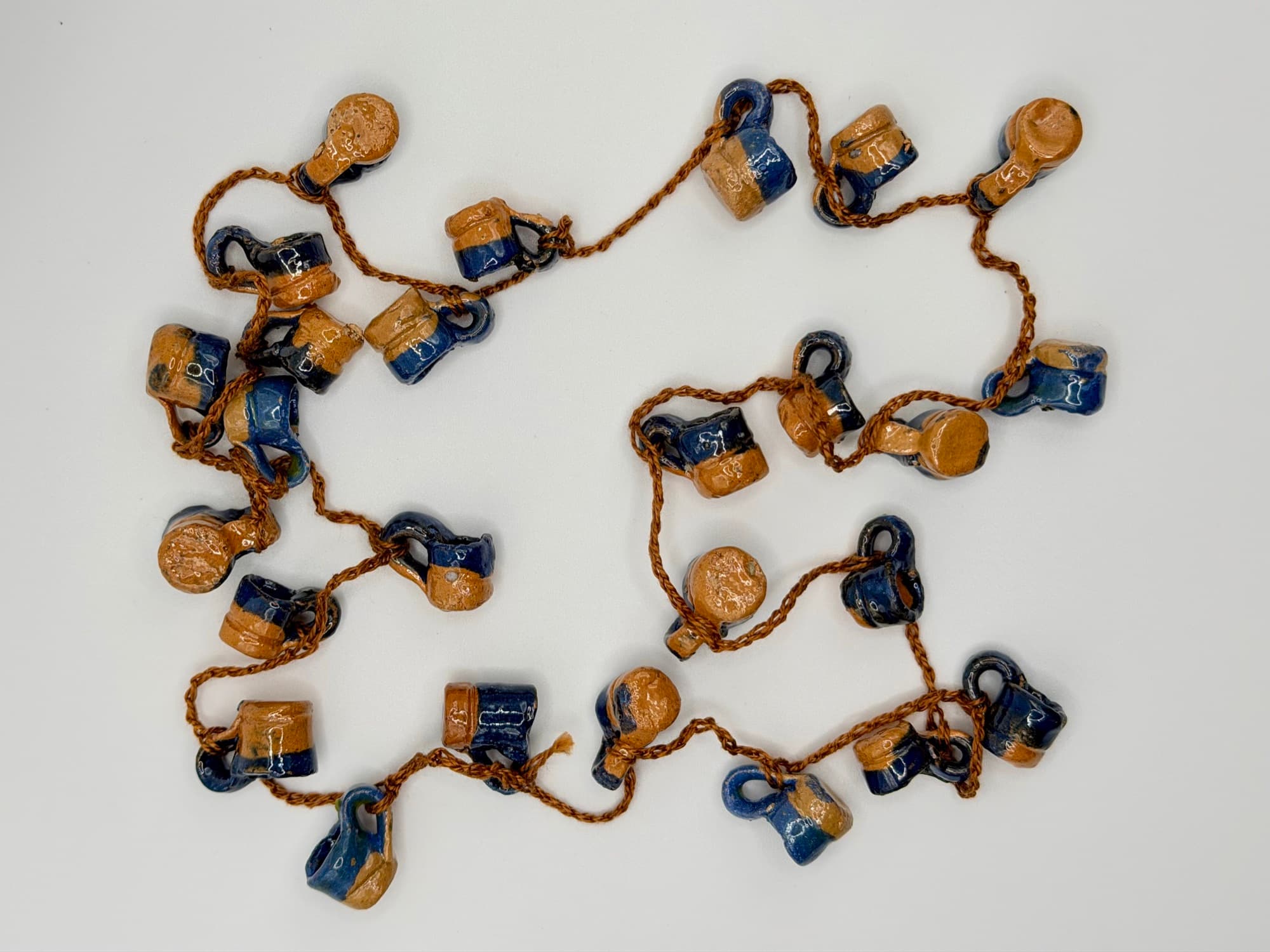 Agua del Río, a 33-inch collar of blue and natural clay jarritos laid flat on a white background.